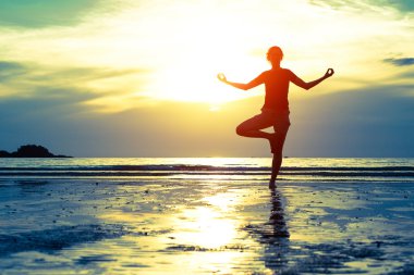 Kadın plajda yoga yapıyor.