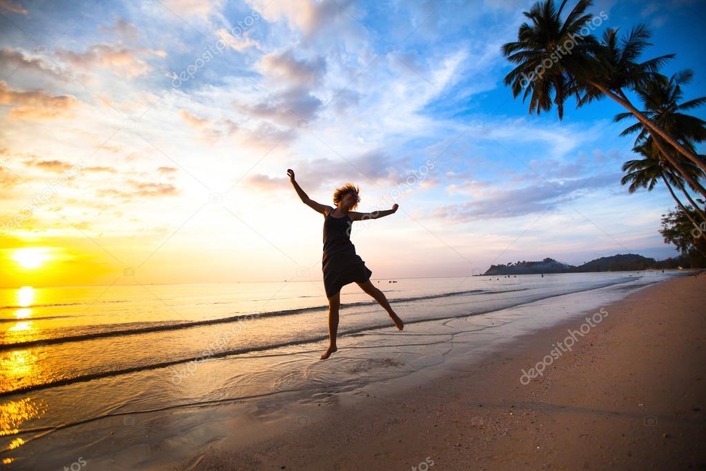 Young girl in a jump on the sea beach at sunset.