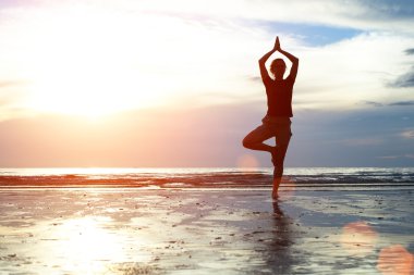 gün batımında sahilde Yoga uygulamak