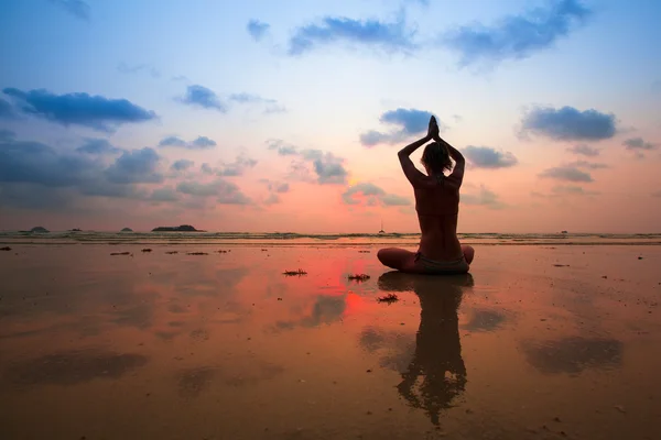 Jonge vrouw silhouet beoefenen van yoga op het strand bij zonsondergang — Stockfoto