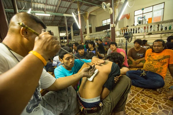 NAKHON CHAI, TAILANDIA - 23 DE MARZO: Un monje no identificado hace tatuajes tradicionales de Yantra durante la ceremonia del Día del Maestro Wai Kroo en Wat Bang Pra el 23 de marzo de 2013 en Nakhon Chai, Tailandia . — Foto de Stock