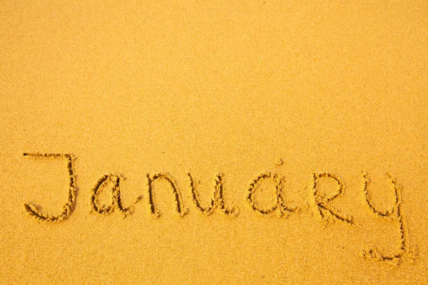 Gennaio - scritto in sabbia su texture spiaggia (per sfondo ) — Foto Stock