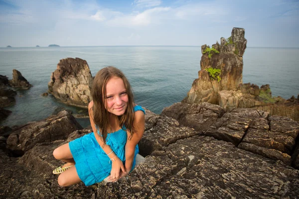 Adolescente em um vestido azul nas rochas da costa na Tailândia . — Fotografia de Stock