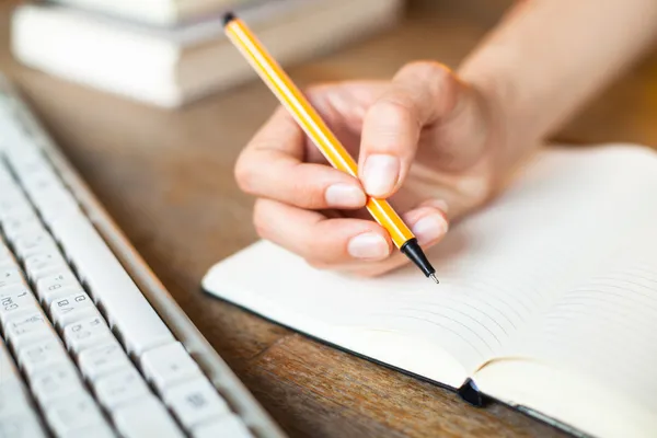 Χέρια γράφει ένα στυλό σε ένα σημειωματάριο, πληκτρολόγιο του υπολογιστή και μια στοίβα από βιβλία — Φωτογραφία Αρχείου