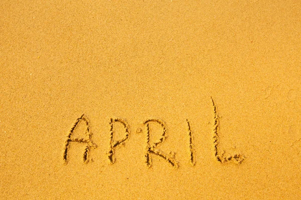 April - geschrieben in Sand auf Strand Textur — Stockfoto