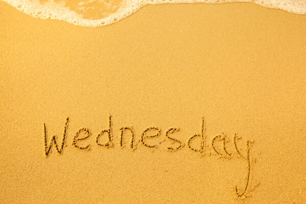 Wednesday - written in sand on beach texture