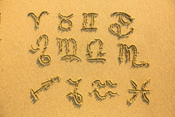 Ensemble de signes du zodiaque dessinés sur le sable de la plage de facture . — Photo