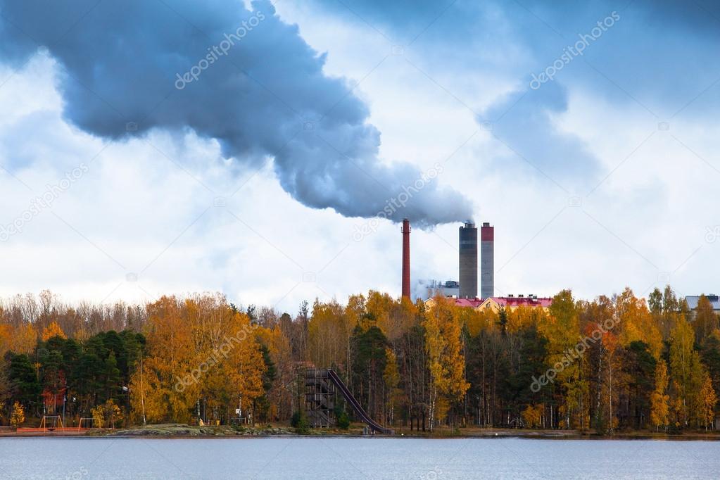 Air pollution by smoke coming out of three factory chimneys