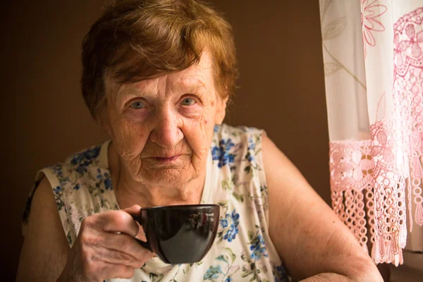 Old woman is drinking tea — Stock Photo, Image