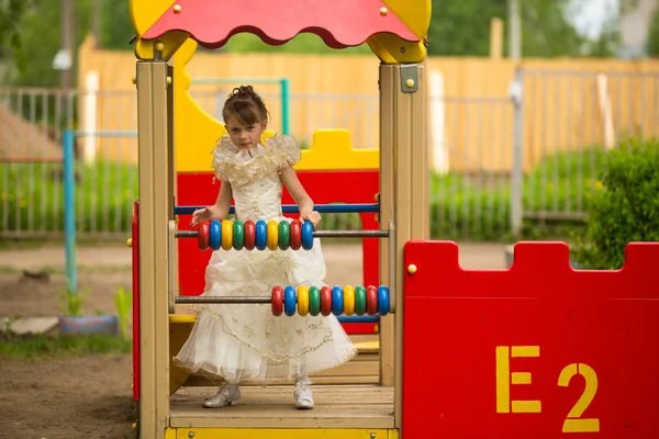 Kleines hübsches Mädchen im eleganten Kleid auf dem Spielplatz — Stockfoto