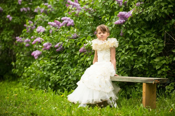 Schönes Mädchen sitzt auf einer Bank im Garten. — Stockfoto