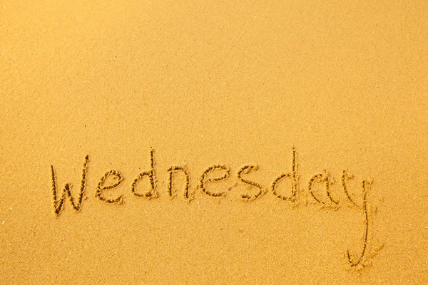 Wednesday - written in sand on beach texture. — Stock Photo, Image