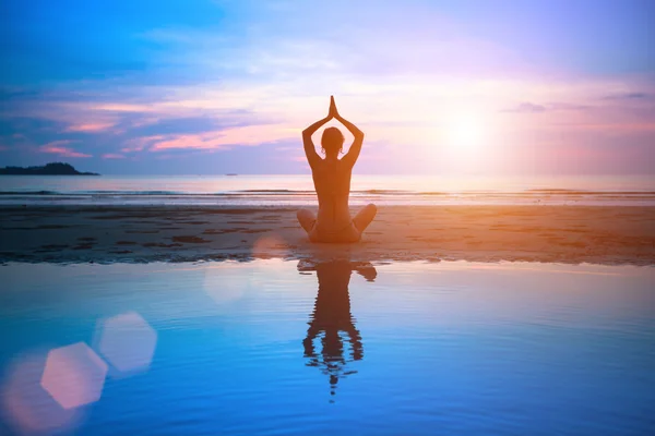 Silhouette junge Frau übt Yoga am Strand bei Sonnenuntergang — Stockfoto