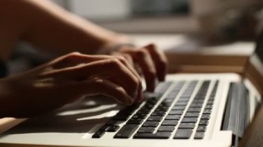 Dizüstü bilgisayarda klavye kullanan genç bir kadının yakın çekimi.