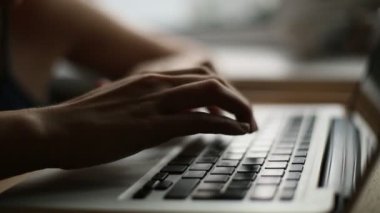 Dizüstü bilgisayarda klavye kullanan genç bir kadının yakın çekimi.