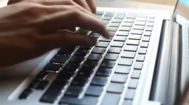 Dizüstü bilgisayarda klavye kullanan genç bir kadının yakın çekimi.