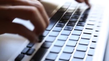 Dizüstü bilgisayarda klavye kullanan genç bir kadının yakın çekimi.