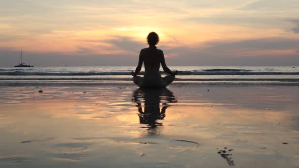 junge Yoga-Frau meditiert in Lotus-Pose am Strand bei Sonnenuntergang