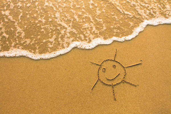 Een zon getekend in het zand van het strand. — Stockfoto