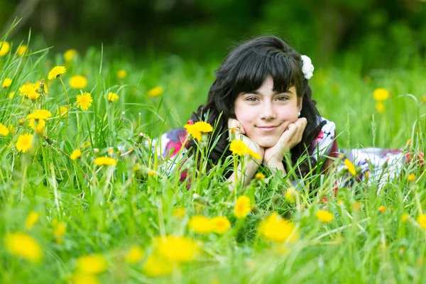 Ganska ung flicka liggande i gräset i parken — Stockfoto