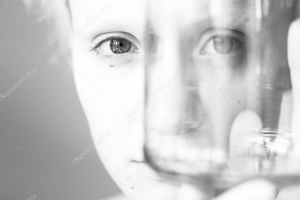 Young girl looks through the empty glass, black and white photo.