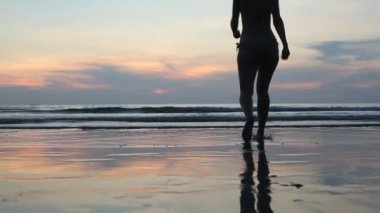 genç bir kadın günbatımı, arkadan aydınlatmalı denize girer