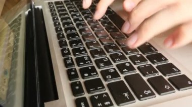 Dizüstü bilgisayarda klavye kullanan genç bir kadının yakın çekimi.