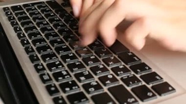Dizüstü bilgisayarda klavye kullanan genç bir kadının yakın çekimi.
