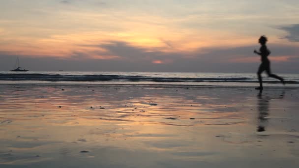 Giovane donna che corre al tramonto sulla riva del mare — Video Stock