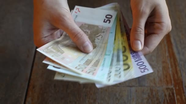 Μετρώντας τα χρήματα στο χέρι σε ξύλινο τραπέζι φόντο — Αρχείο Βίντεο