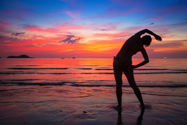Donna che fa esercizio sulla spiaggia vicino all'oceano al tramonto in Thailandia — Foto Stock