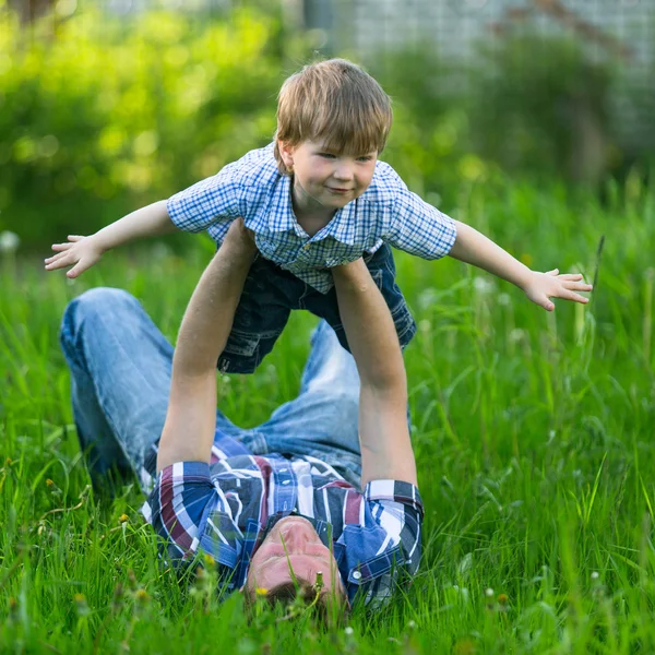 Pai brincando na grama com seu filho pequeno — Fotografia de Stock