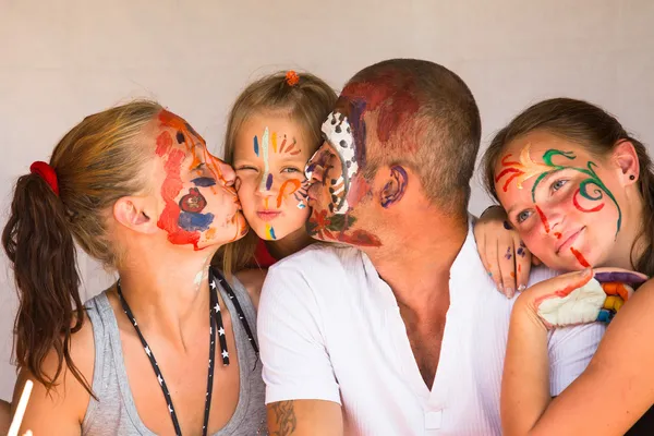 Szczęśliwa rodzina - młoda para całuje młodszego dziecka córka, po zagraniu z farby — Zdjęcie stockowe
