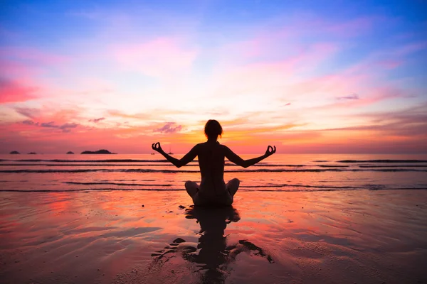 Zonsondergang yoga vrouw op zee kust. Stockafbeelding