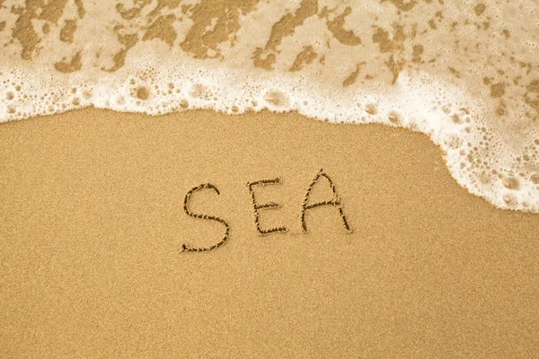 Zee - geschreven door hand in zand op een strand, met een zachte Golf. — Stockfoto