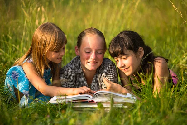 Porträtt av söta barn läser bok i naturlig miljö tillsammans. — Stockfoto