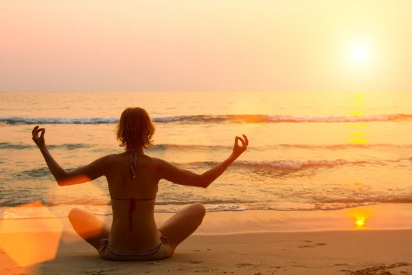Jeune femme pratiquant le yoga sur la plage. — Photo