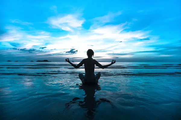 Deniz kıyısında gün batımı yoga kadını