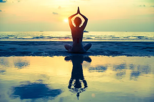 Mujer de yoga sentada en pose de loto en la playa — Foto de Stock