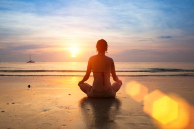 gün batımında sahilde Yoga uygulamak siluet genç kadın