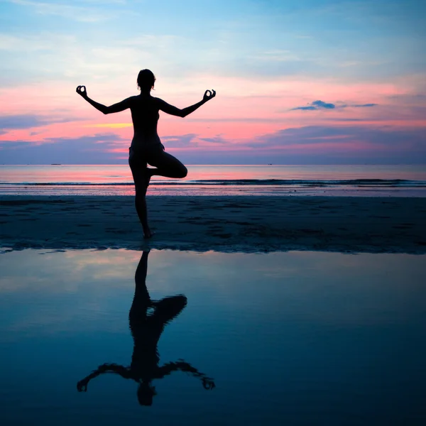 Silhueta de uma mulher ioga no por do sol do mar com reflexão na água . — Fotografia de Stock