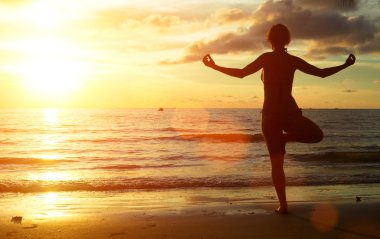 Sahilde günbatımı sırasında Yoga kadınla.