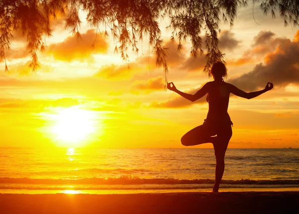 Junge Frau praktiziert Yoga bei Sonnenuntergang an der Küste Thailands — Stockfoto