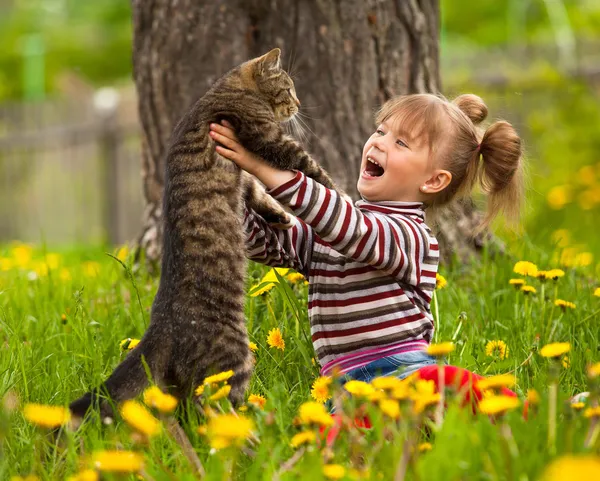 Emoční holčička hraje s kočkou v parku. — Stock fotografie