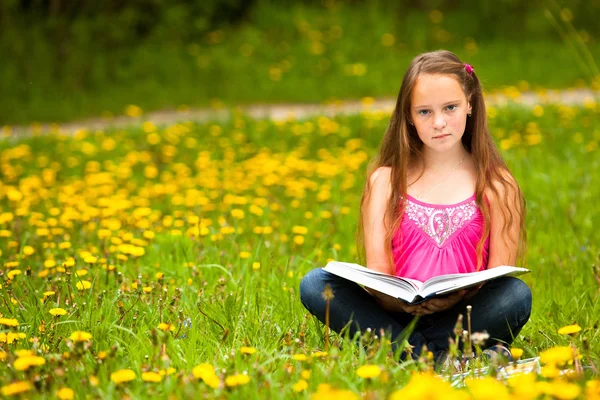 Kız bir çim üzerinde oturur ve kitap okur — Stok fotoğraf