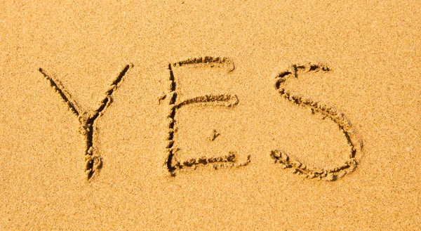 Sim - escrito em areia na textura da praia . — Fotografia de Stock