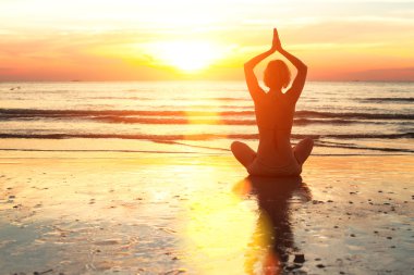gün batımında sahilde Yoga uygulamak siluet genç kadın