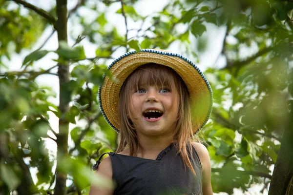 Menina encantadora posando em um chapéu de palha no parque . — Fotografia de Stock