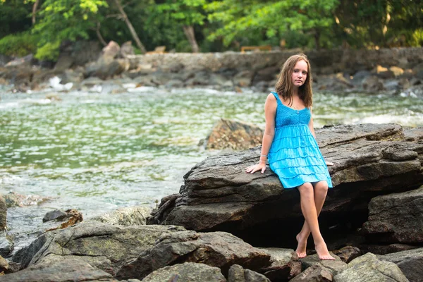 Adolescente en robe bleue dans les rochers de la côte . — Photo