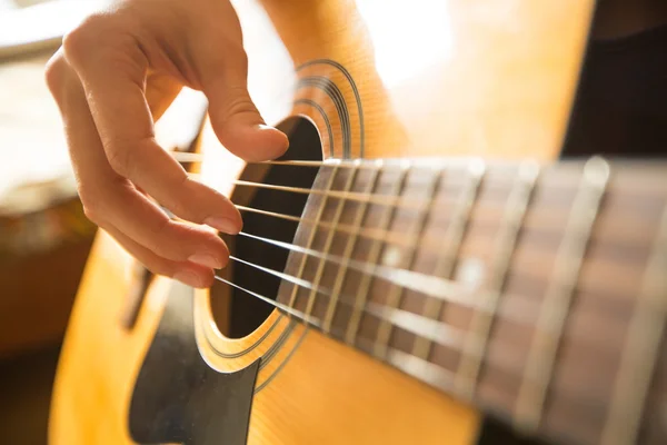 Weibliche Hand spielt auf der Akustikgitarre. Nahaufnahme. — Stockfoto